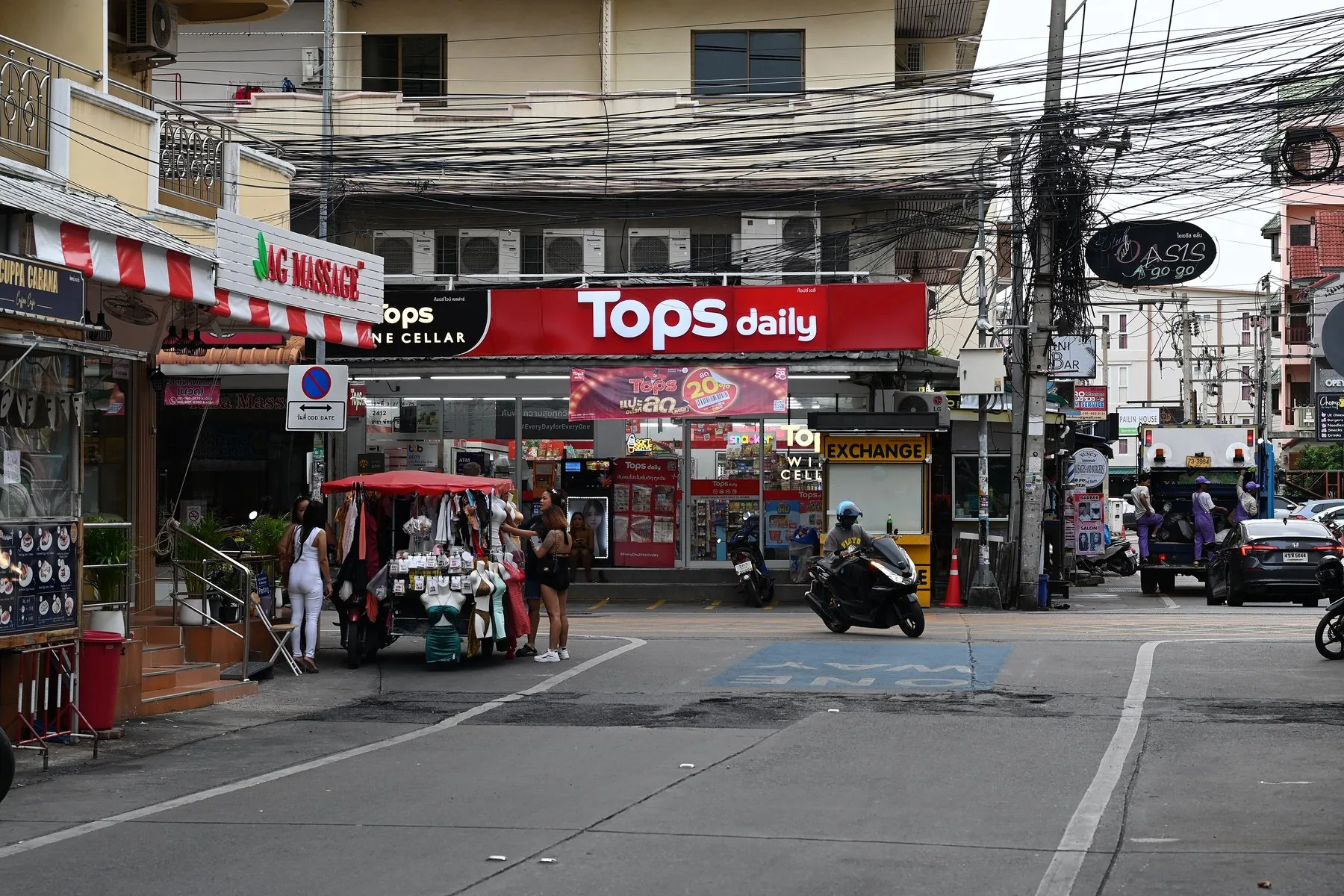 Motorcykler, tuk-tuk og fodgængere i en travl gade i Nong Pla Lai i Pattaya