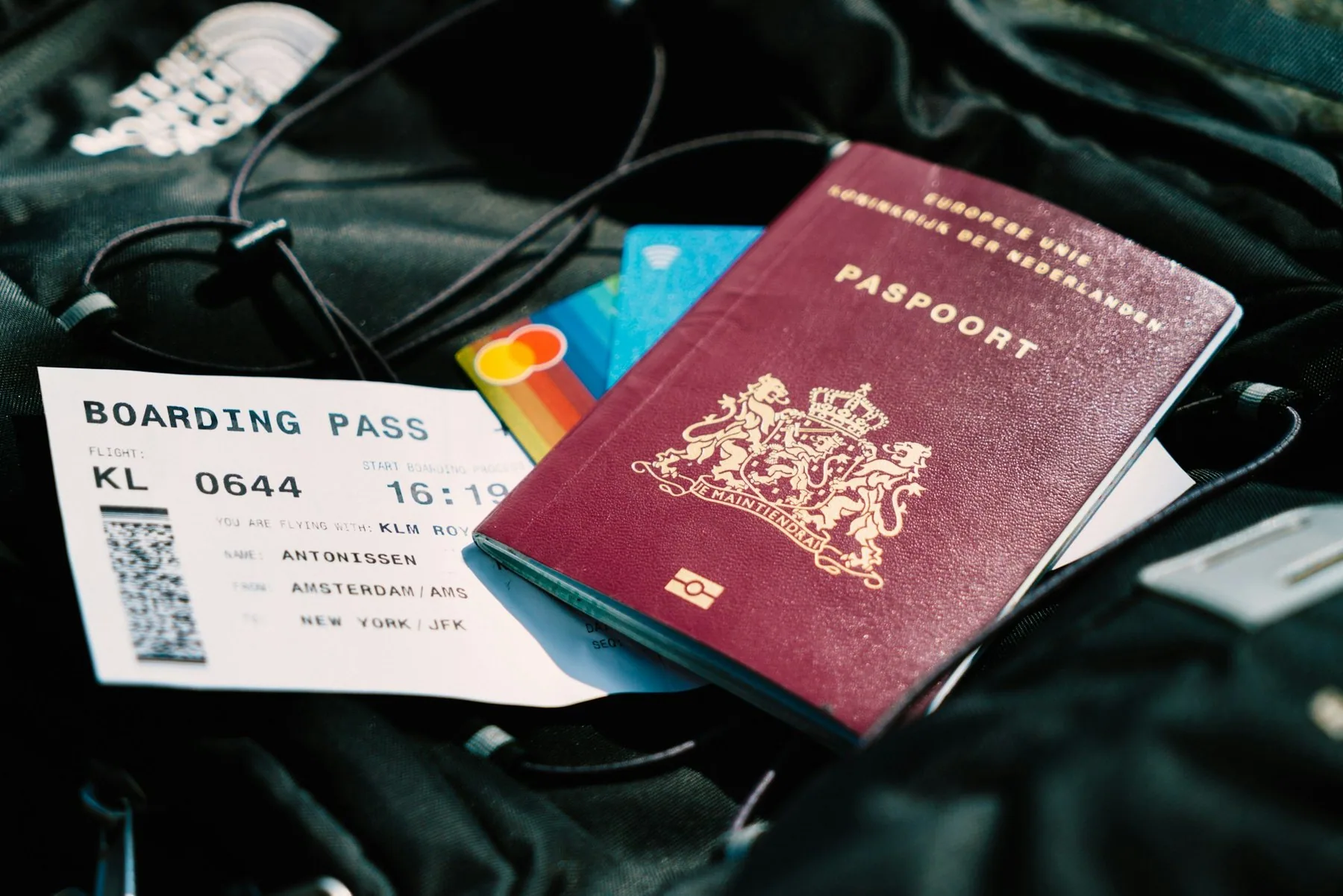 Rött pass, betalkort och boardingkort på en svart resväska