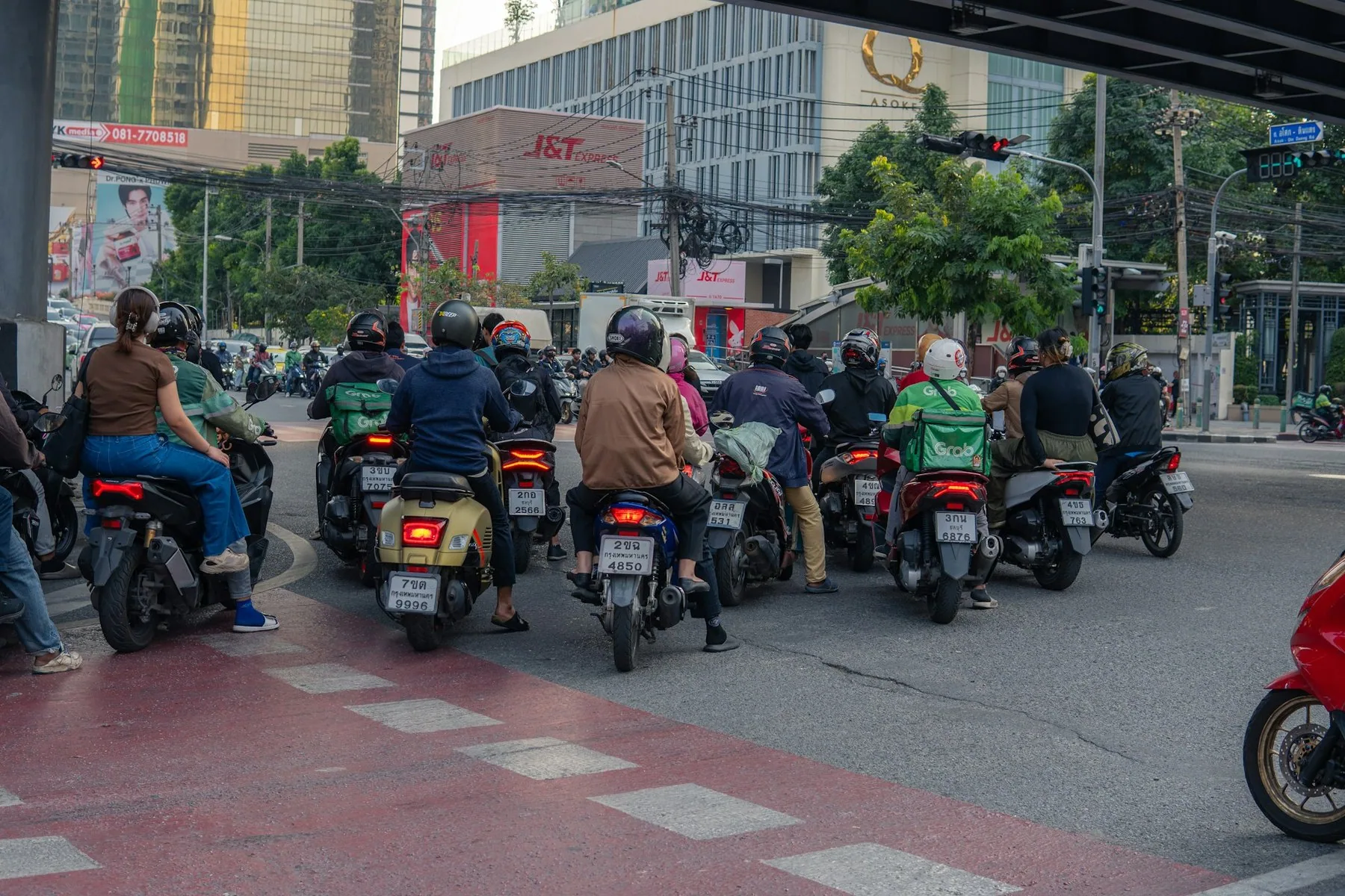 Många motorcyklar väntar i en trafikkorsning i en thailändsk stad
