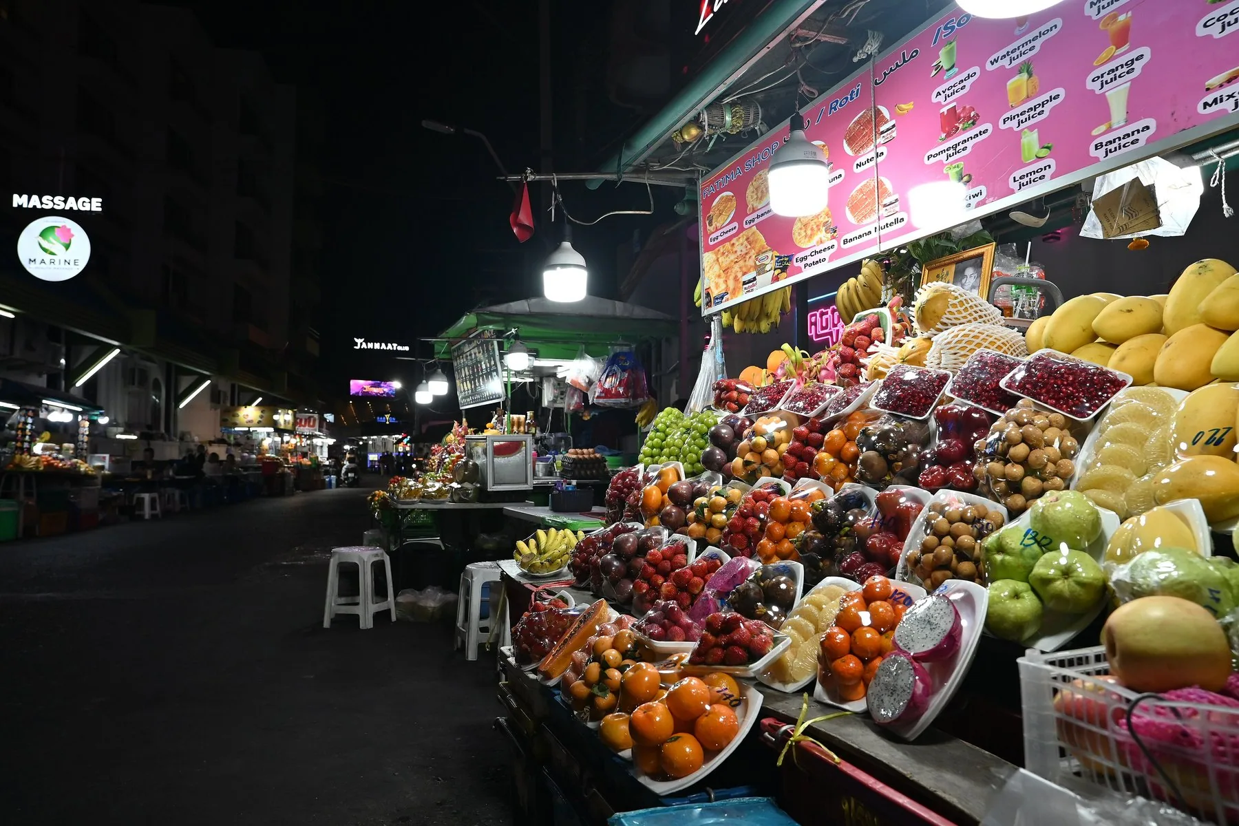 Fruktstånd med mango, drakfrukt och mandariner på kvällen i Nong Pla Lai i Pattaya