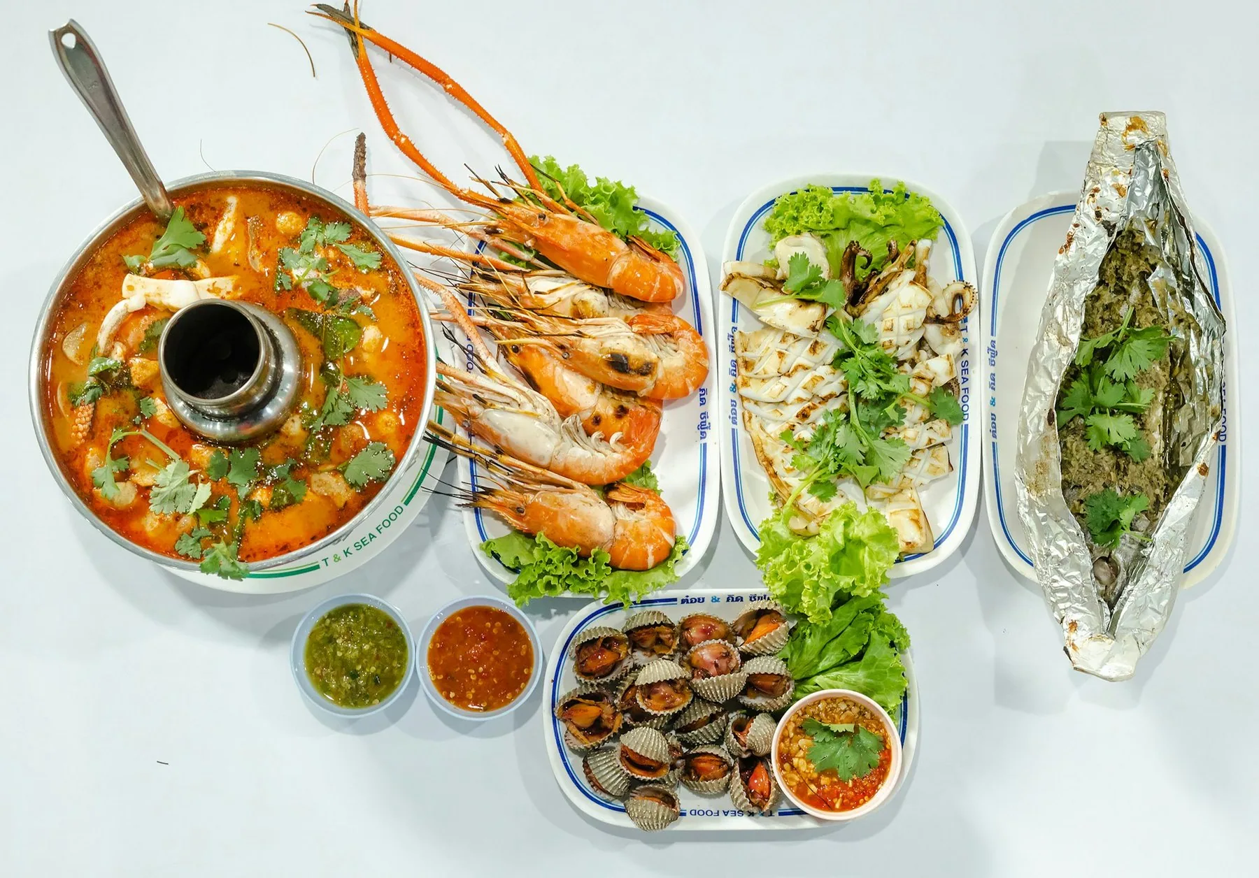 Tom yum-suppe, grillede reker og fisk i folie på et thailandsk middagsbord