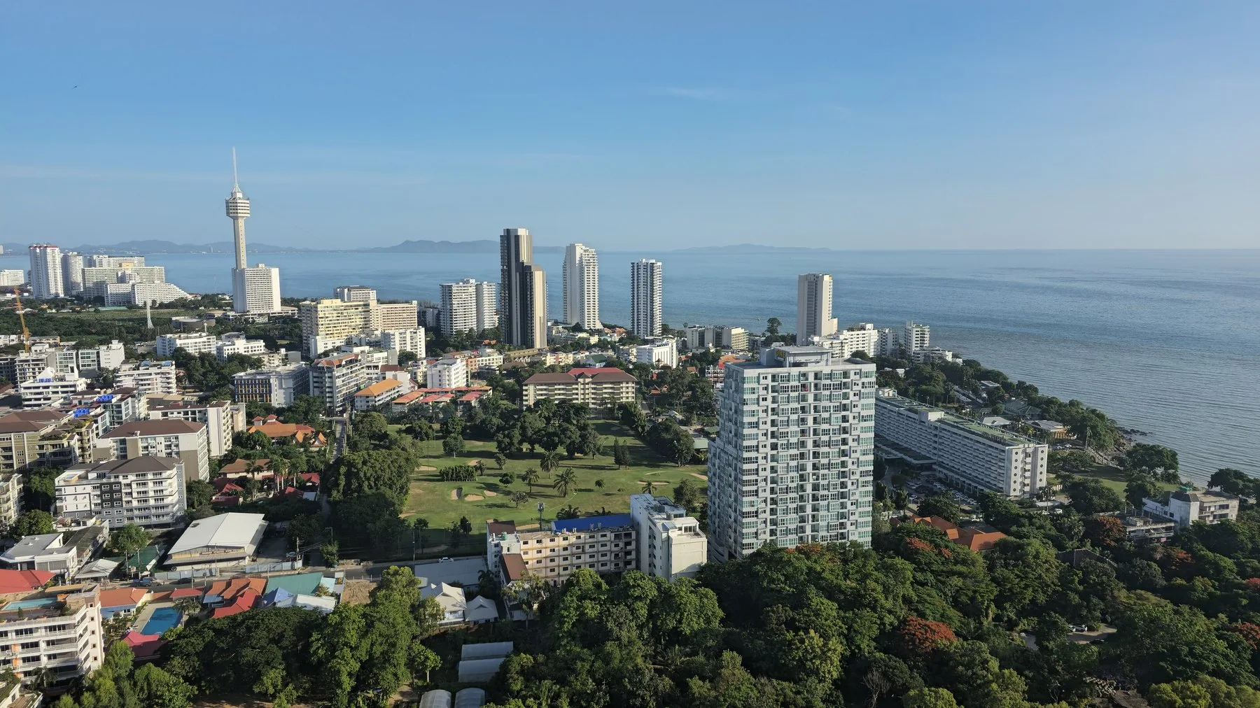 Bostadshus, grönområden och höghus längs kusten söder om Pattaya en klar morgon