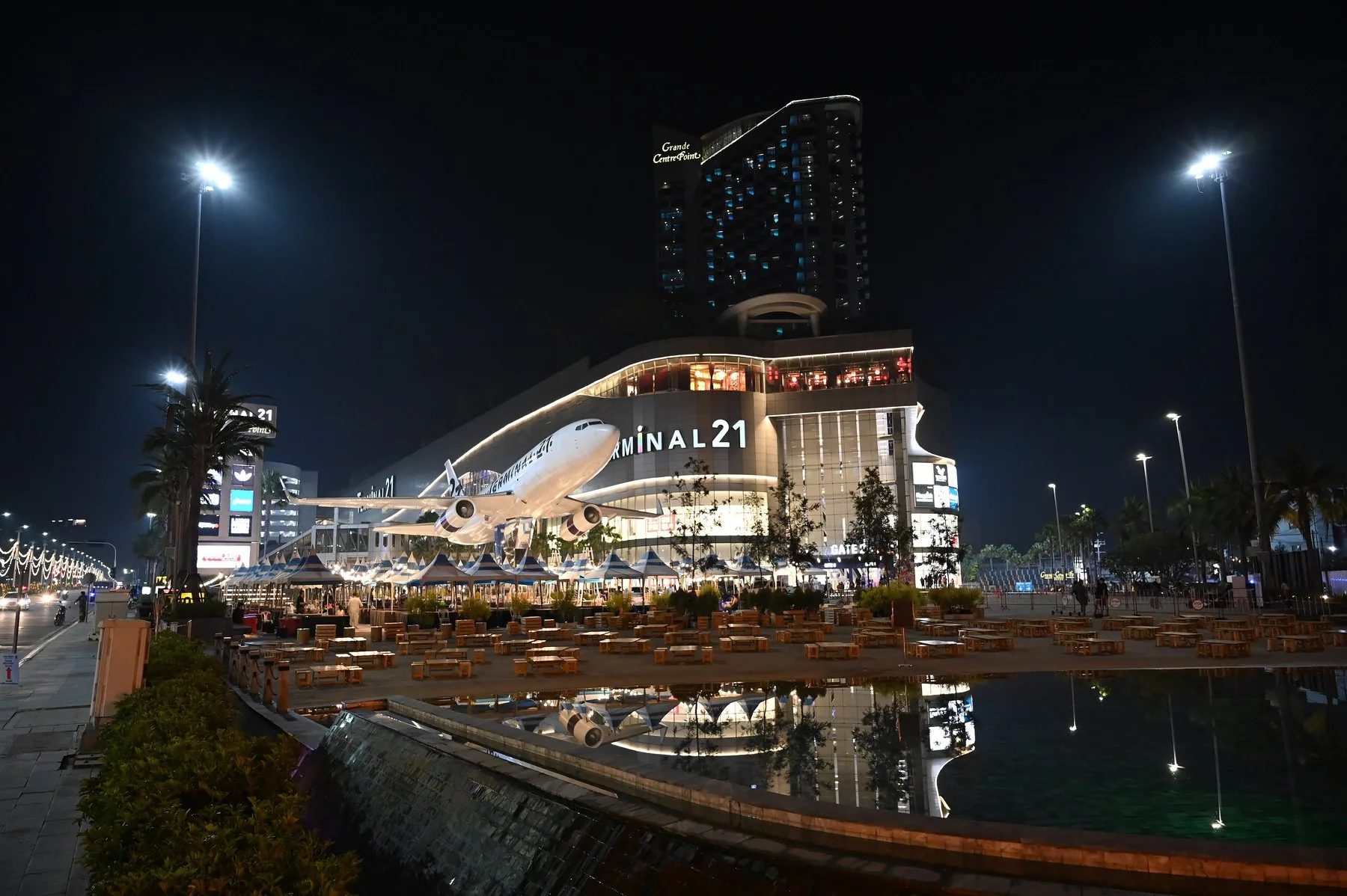 Indkøbscentret Terminal 21 i Nordpattaya oplyst om aftenen med en stor flymodel foran facaden