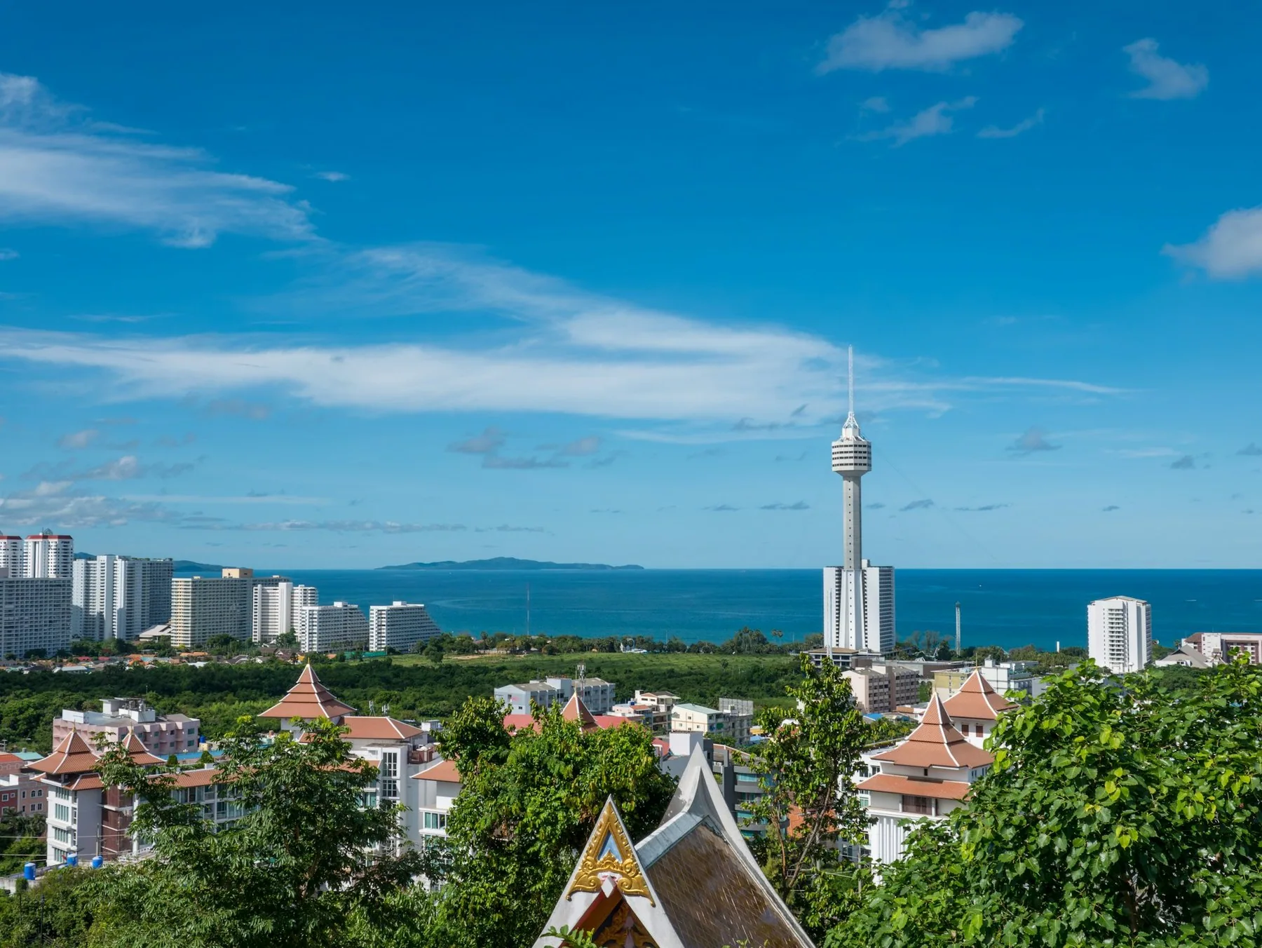 Pattaya Park-tårnet og høyhus ved havet sett fra en høyde med tempeltak i forgrunnen