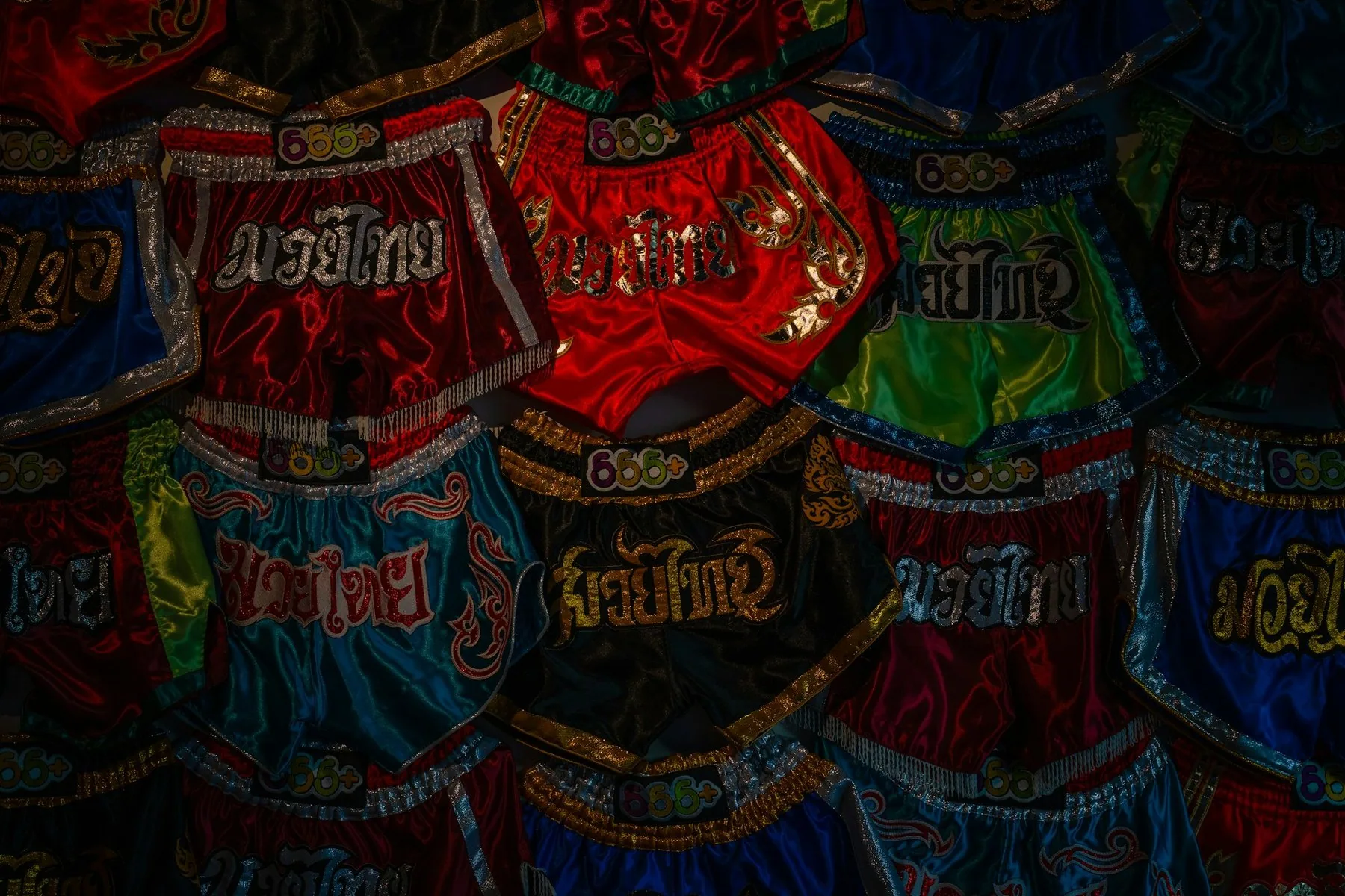 Fargerike muay thai-shorts i sateng med thailandsk skrift
