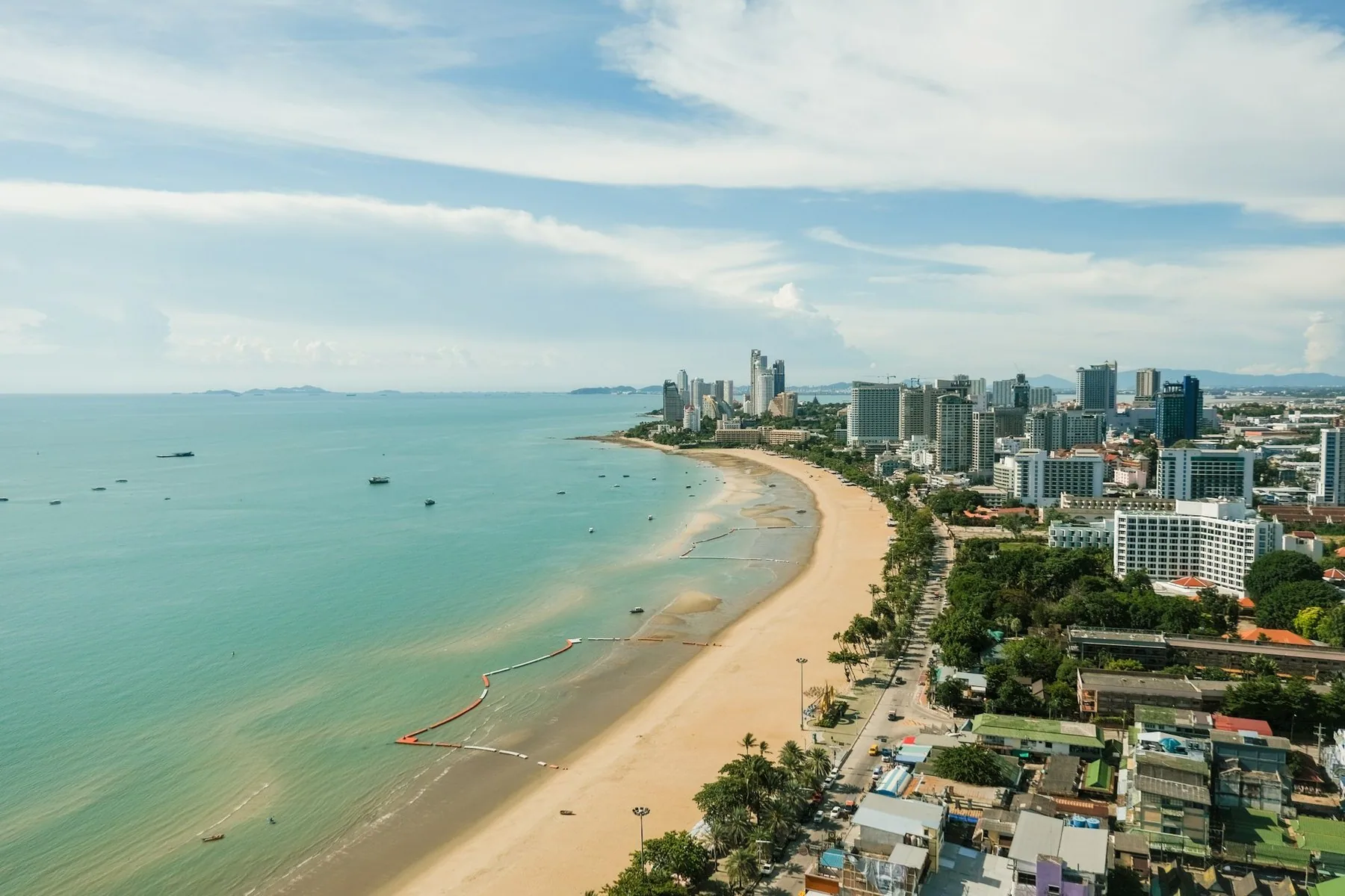 Lang sandstrand og høyhus langs bukta sett ovenfra i Pattaya-området