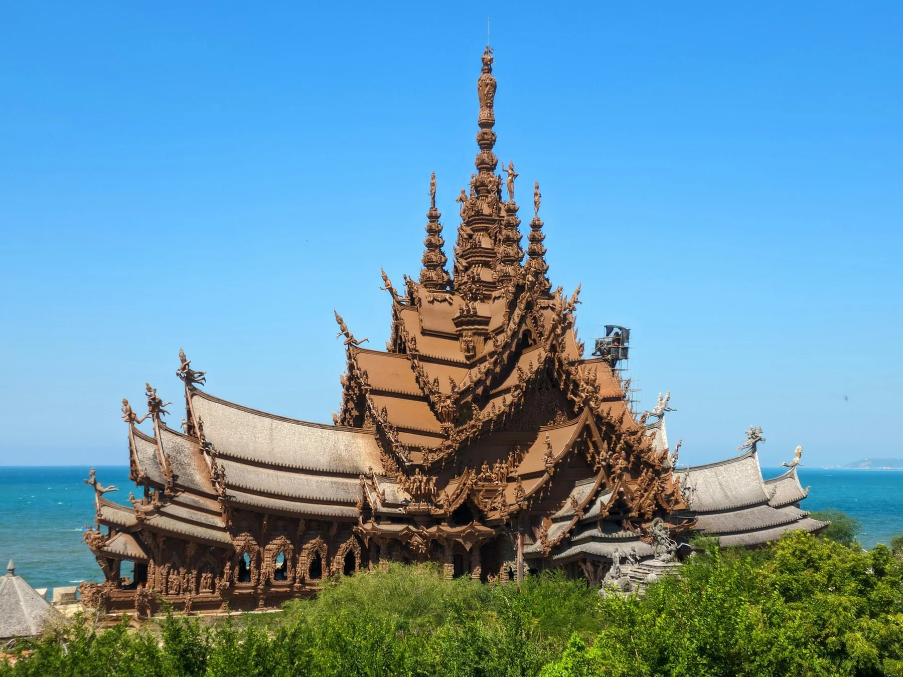 Et udskåret trætempel med høje spir ved havet i Pattaya