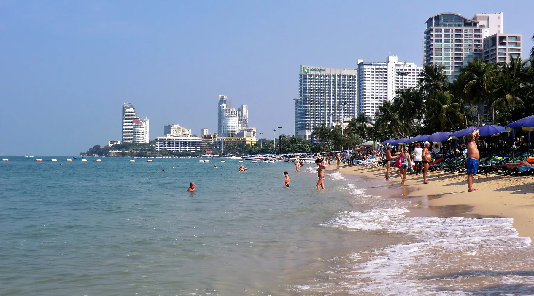 Badende og solsenger på Pattaya Beach under klar blå himmel