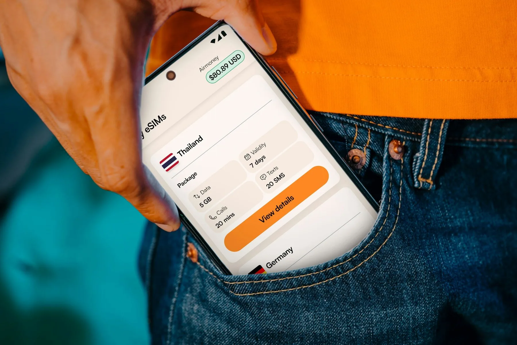 Mobiltelefon med en eSIM-app for Thailand stikker opp av en jeanslomme