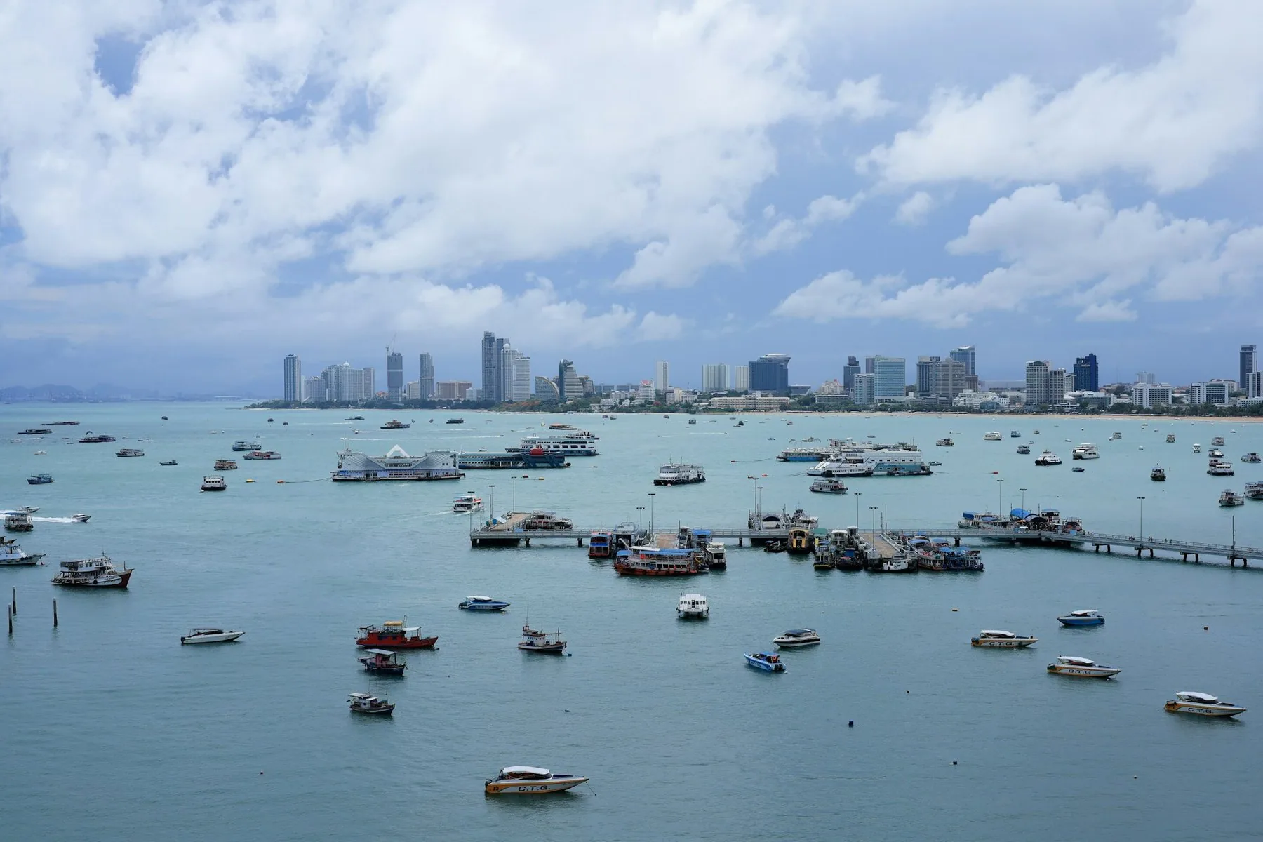 Pattaya-bukta med mange båter og hotelltårn langs kysten en klar dag