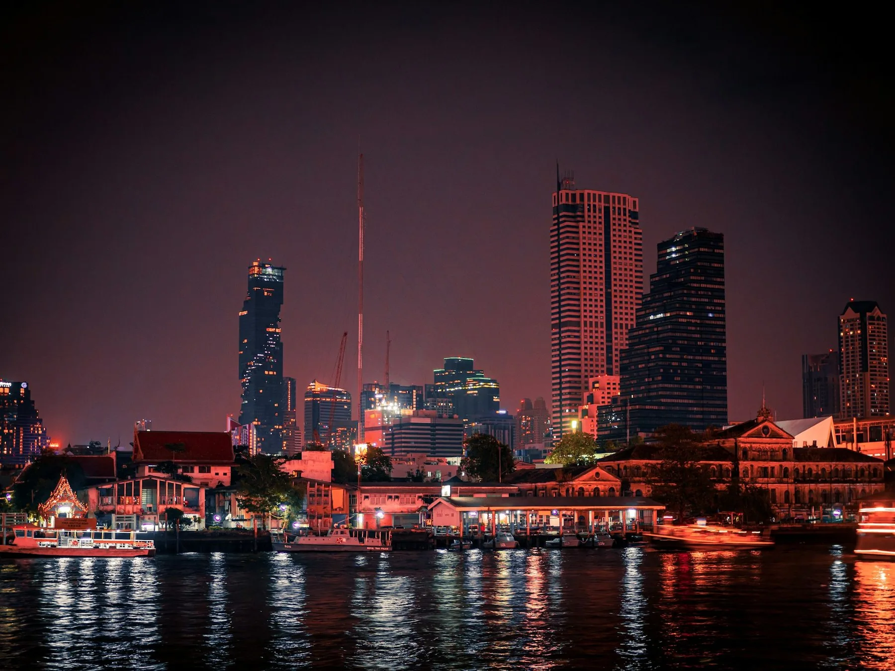 Bangkoks skyline med MahaNakhon speglad i Chao Phraya-floden på kvällen